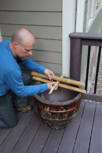 a man placing cut bamboo pieces on top of a large pot
